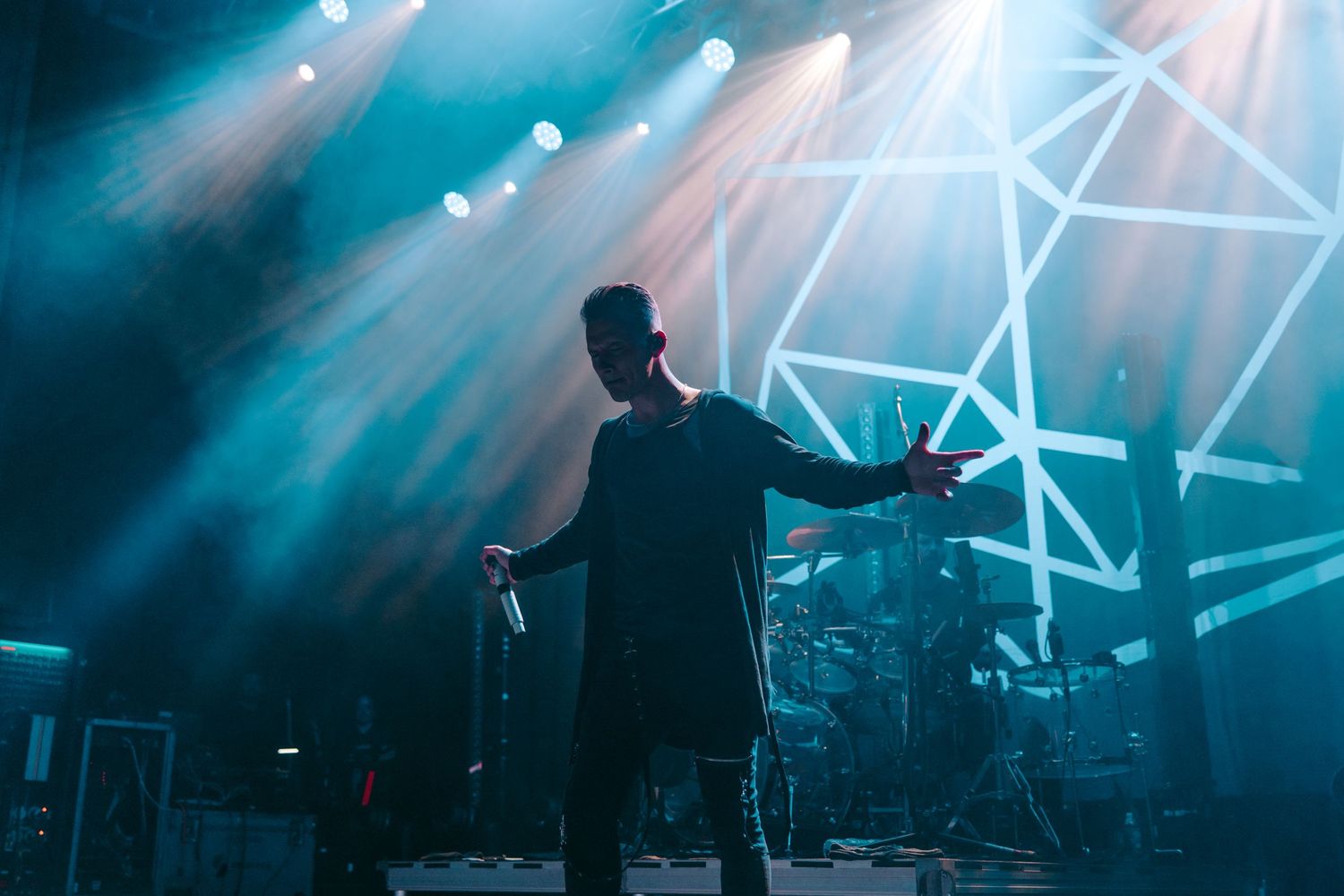 Silhouette of performer on stage with dramatic blue lighting and geometric backdrop.