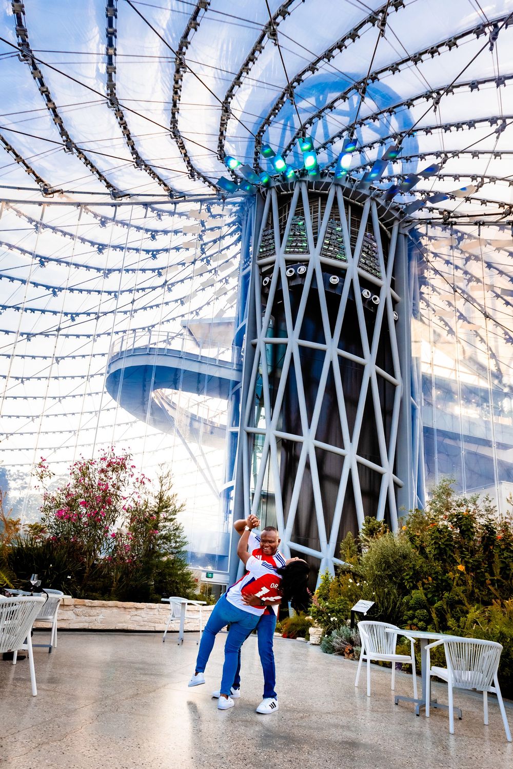 A festive outdoor plaza with strings of lights overhead and modern architectural tower features in downtown Seattle.