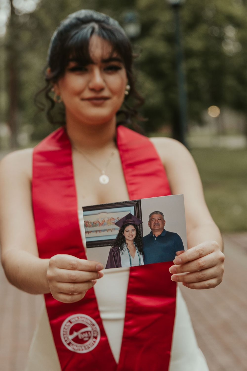 Laura smiles in graduation cap with historic Eastern Washington University Showalter Hall in the background.