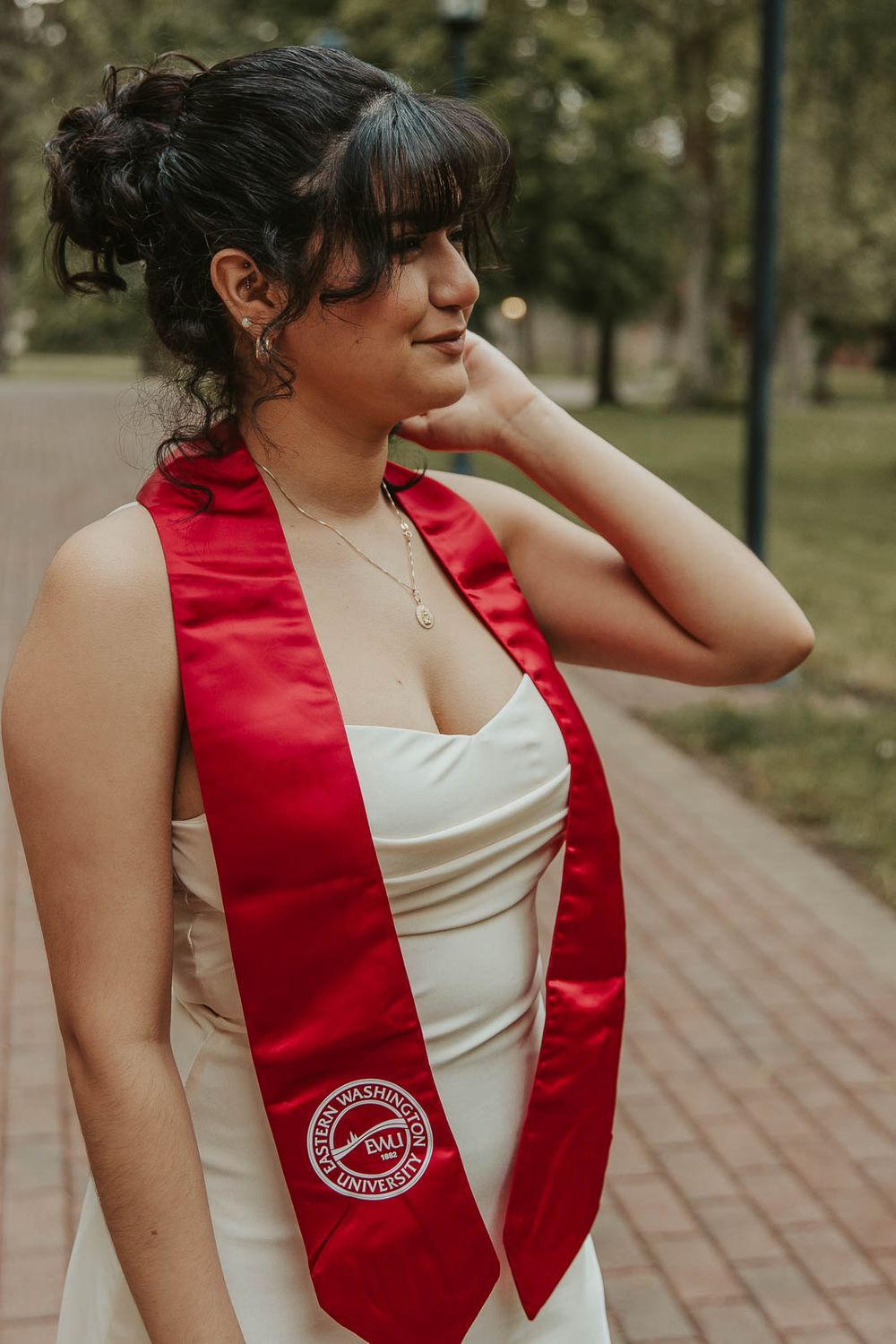 Laura smiles in graduation cap with historic Eastern Washington University Showalter Hall in the background.