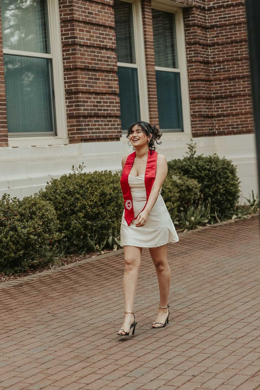 Laura smiles in graduation cap with historic Eastern Washington University Showalter Hall in the background.
