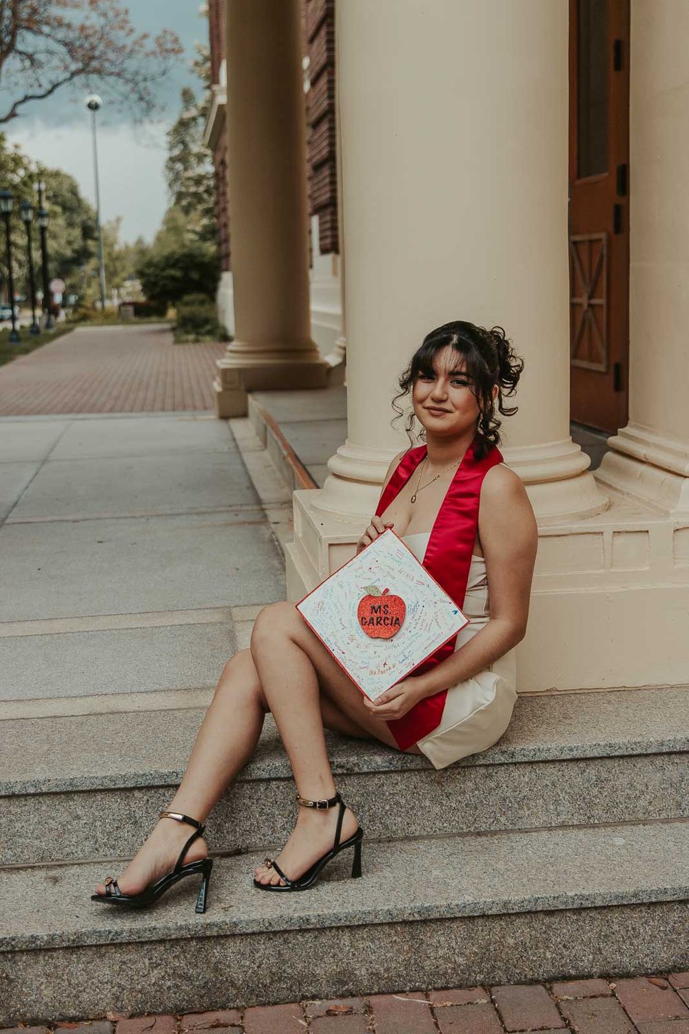 Laura smiles in graduation cap with historic Eastern Washington University Showalter Hall in the background.