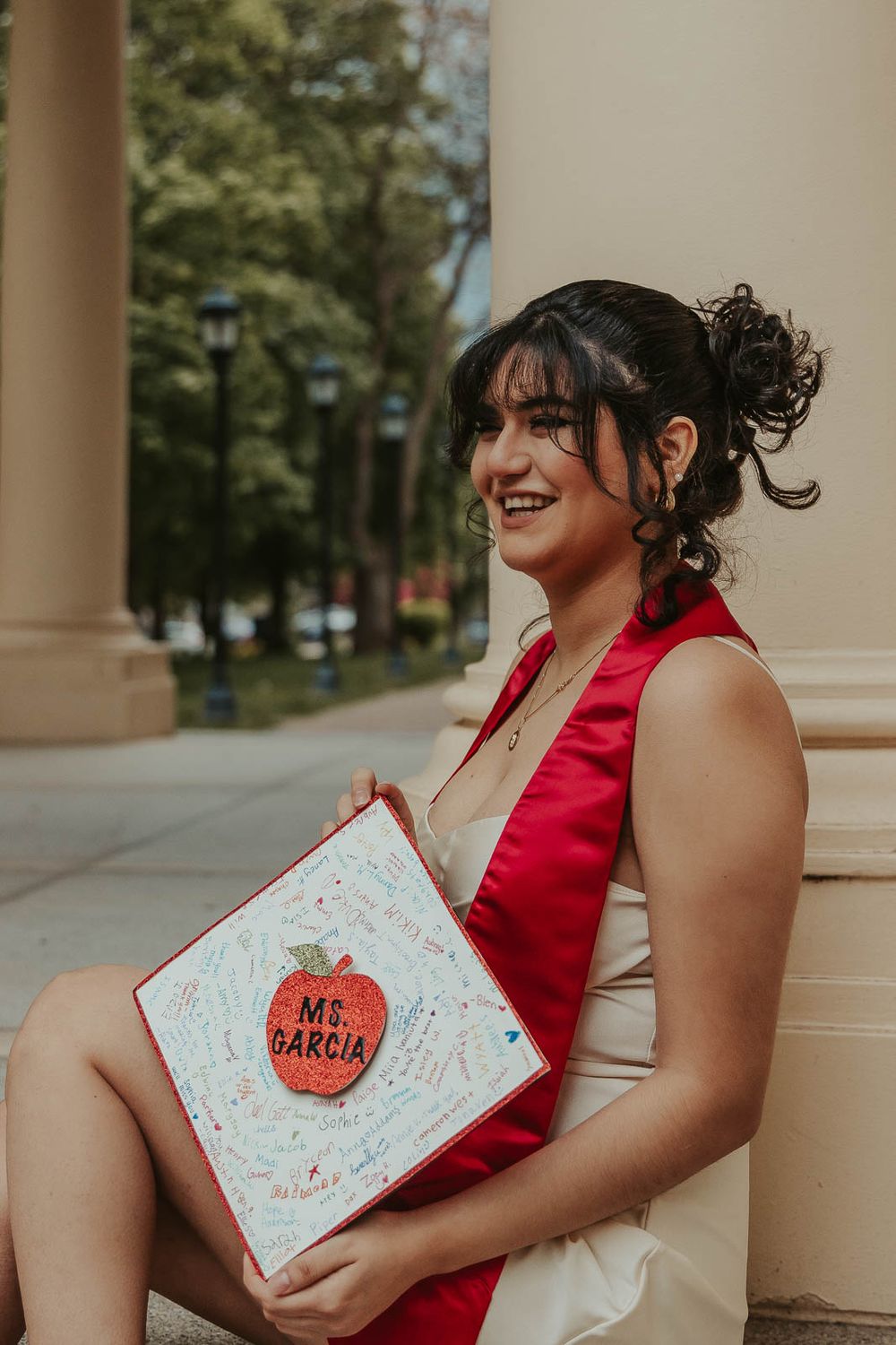 Laura smiles in graduation cap with historic Eastern Washington University Showalter Hall in the background.