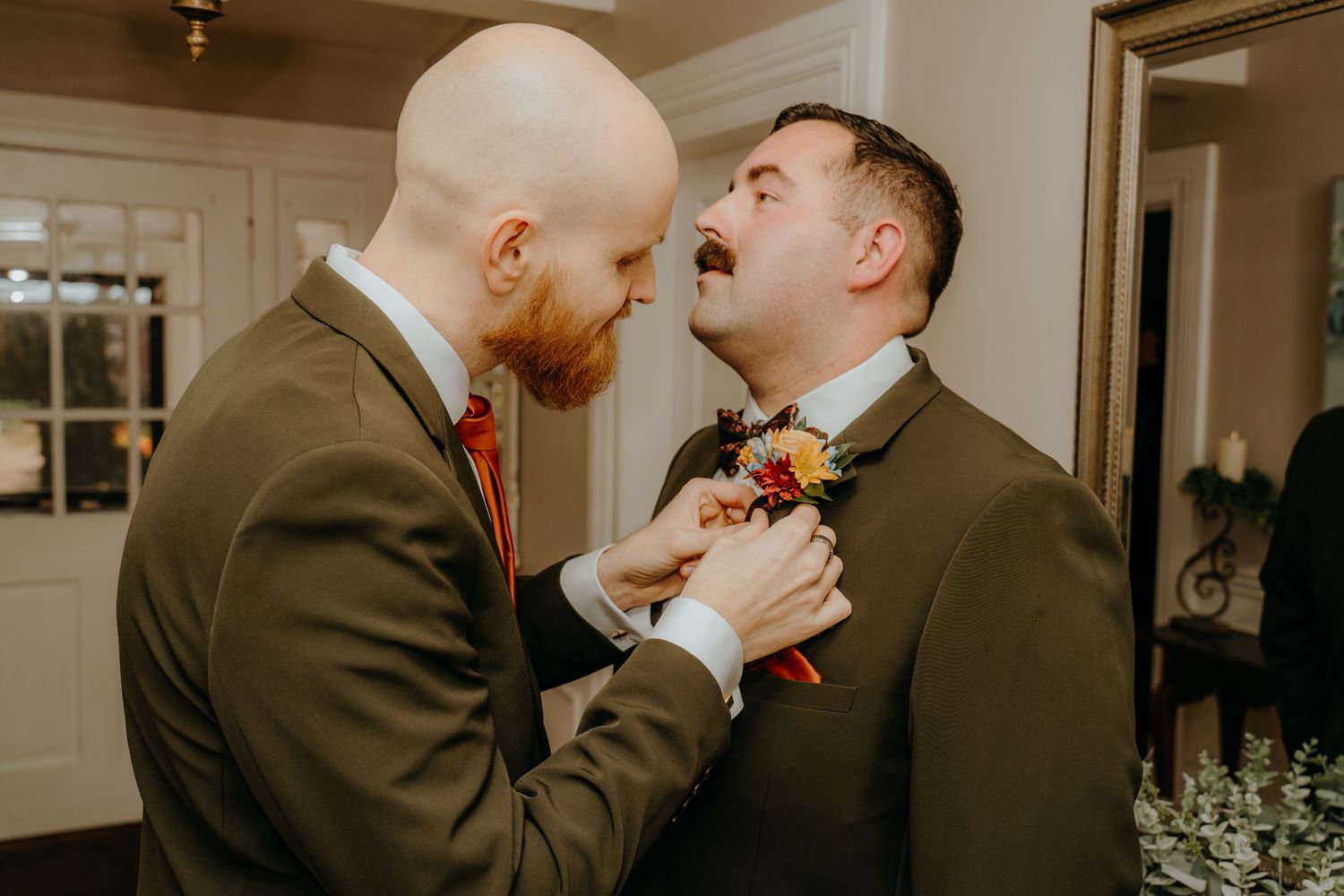 Groomsmen in black suits pose together under white fabric draping at wedding venue.