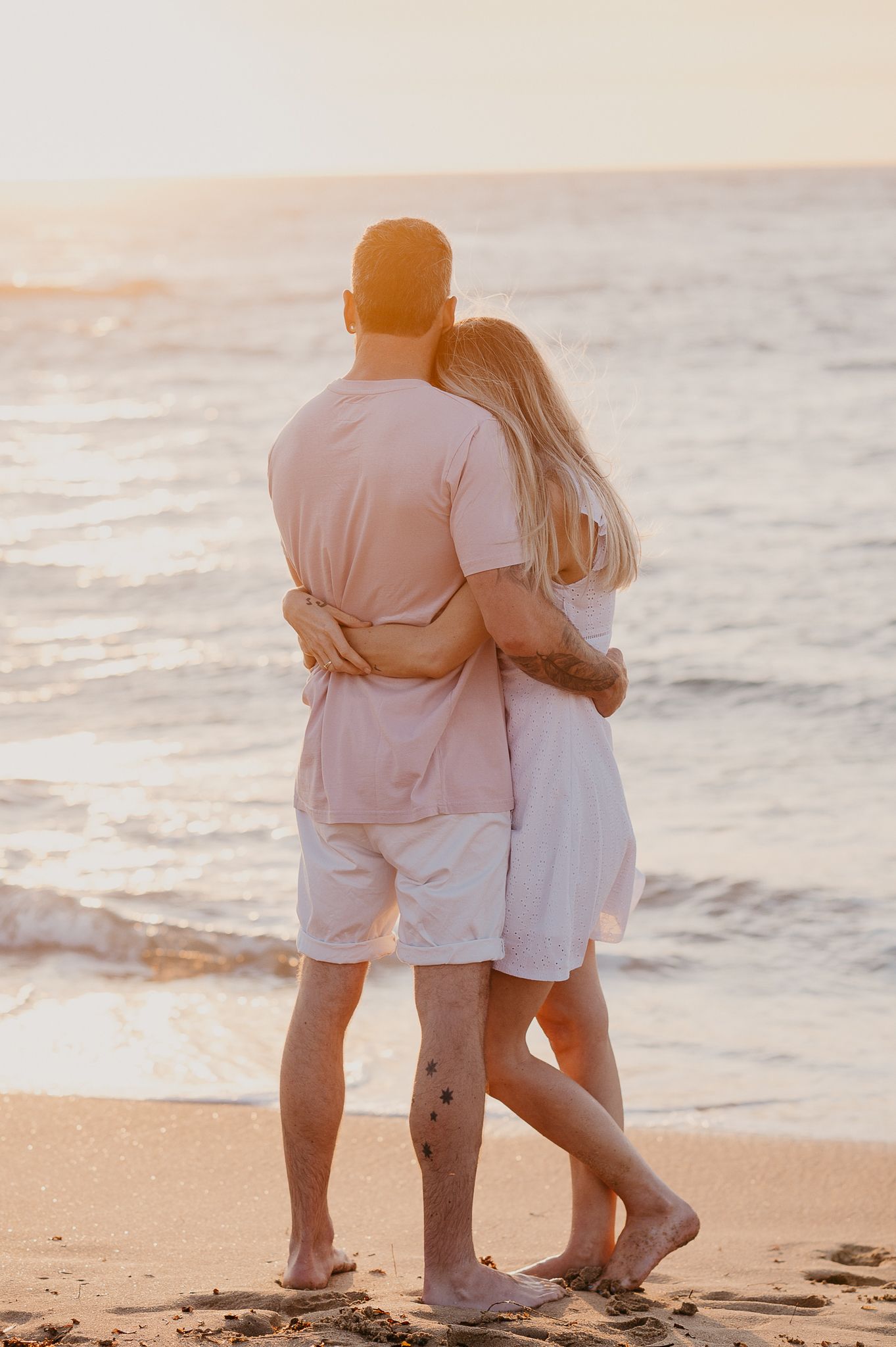 Couple embrace as golden sunset glows across waves at the beach for family photographer Mandurah, Story & Soul Photography Mandurah WA