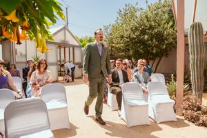 An outdoor wedding ceremony setup with white chairs and desert landscaping on a sunny day.