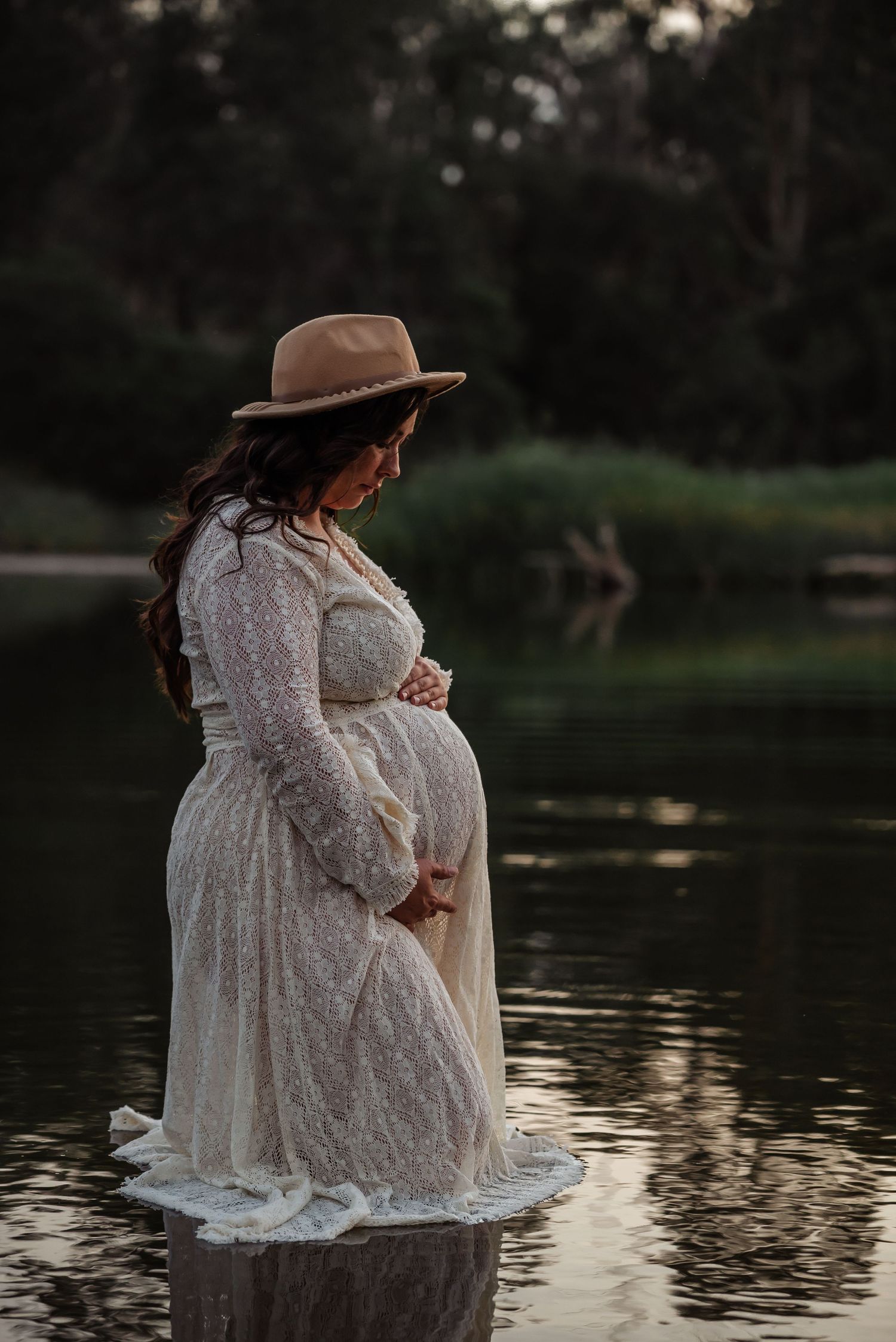 A flowing white dress catches the golden light during a sunset photoshoot in a field.
