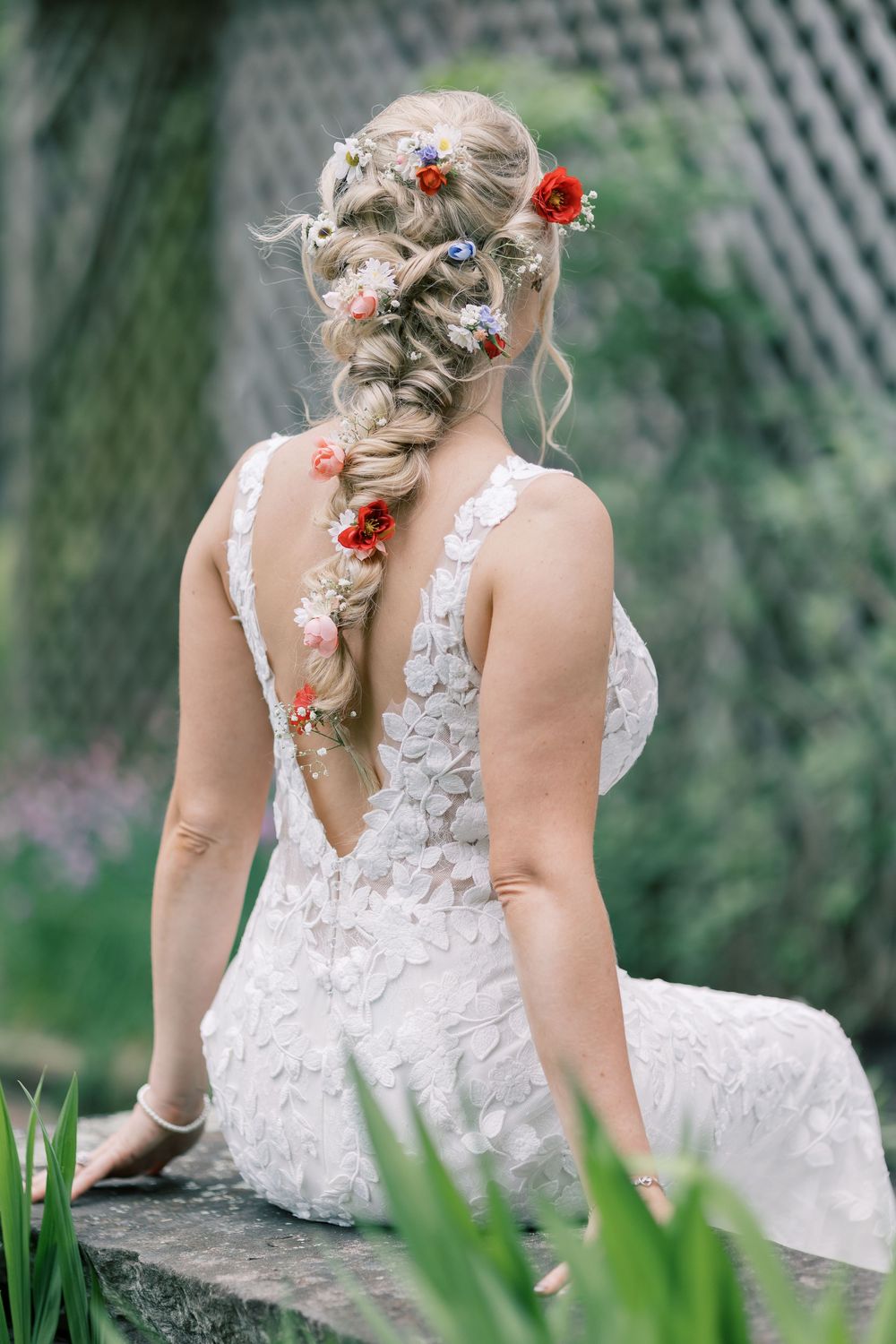 An elegant wedding hairstyle featuring a long braid adorned with delicate coral and pink flowers in Orange County, New York.