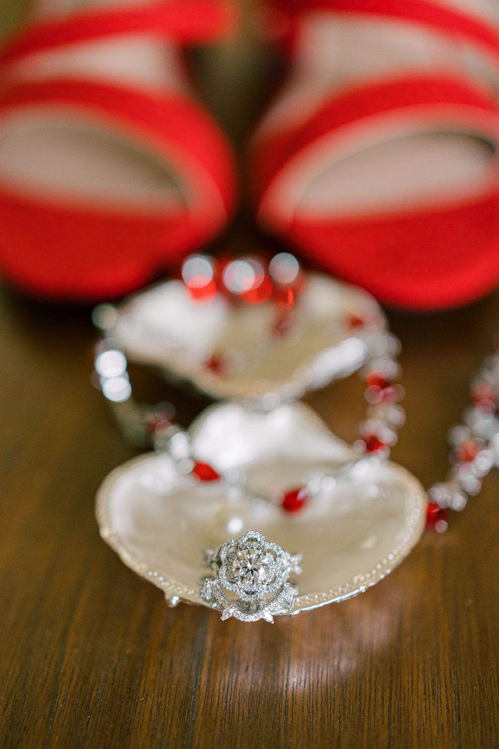 A vintage-inspired diamond engagement ring displayed with red and white decorative elements on a wooden surface in Orange County, New York.