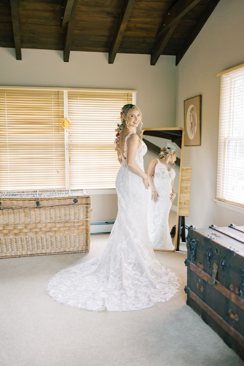 A lace wedding gown with long train displayed in a sunny room with wooden beams in Orange County, New York.