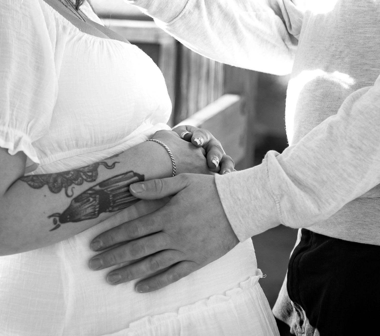 Close-up shots of hands tenderly touching in black and white.