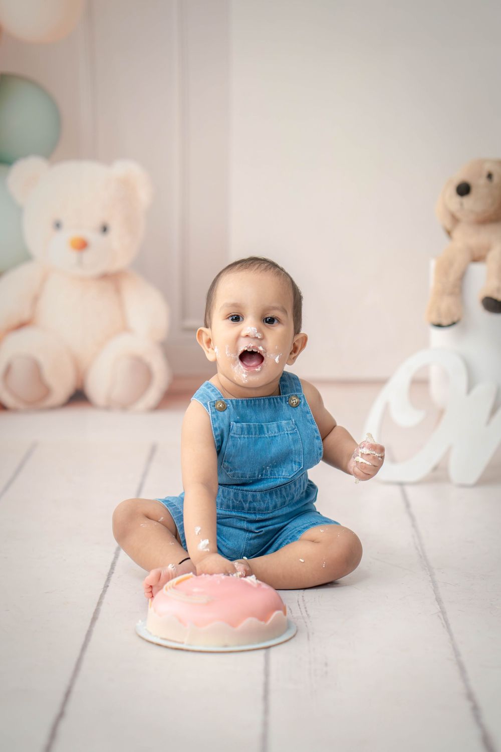"One-year-old laughing with cake crumbs on face and hands"