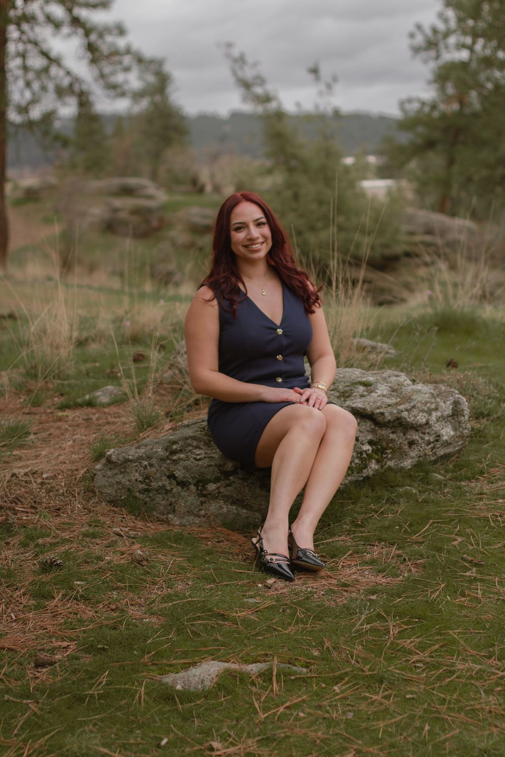 Redhaired girl sitting posed on mossy rock in professional dresswear for Psych headshots at Mirabeau Point Park.