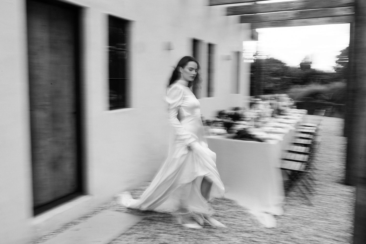 A blurred motion shot of a bride running through a covered outdoor space.
