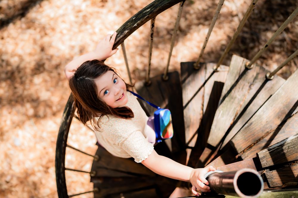 Looking down at a twisting rustic wooden staircase in a wooded outdoor setting.