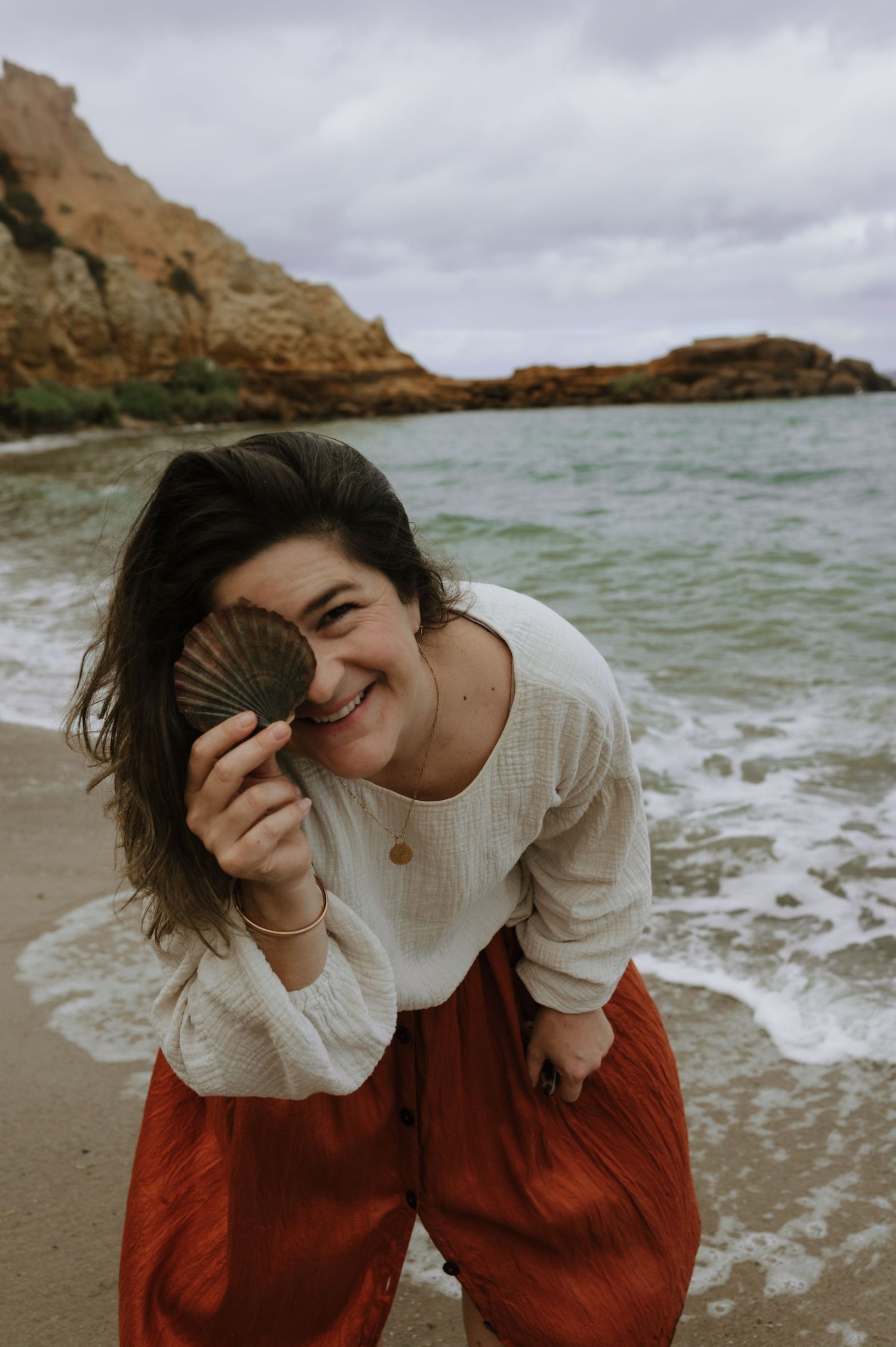 Laura from Laura May Photography having a joyful moment on a rocky beach.
