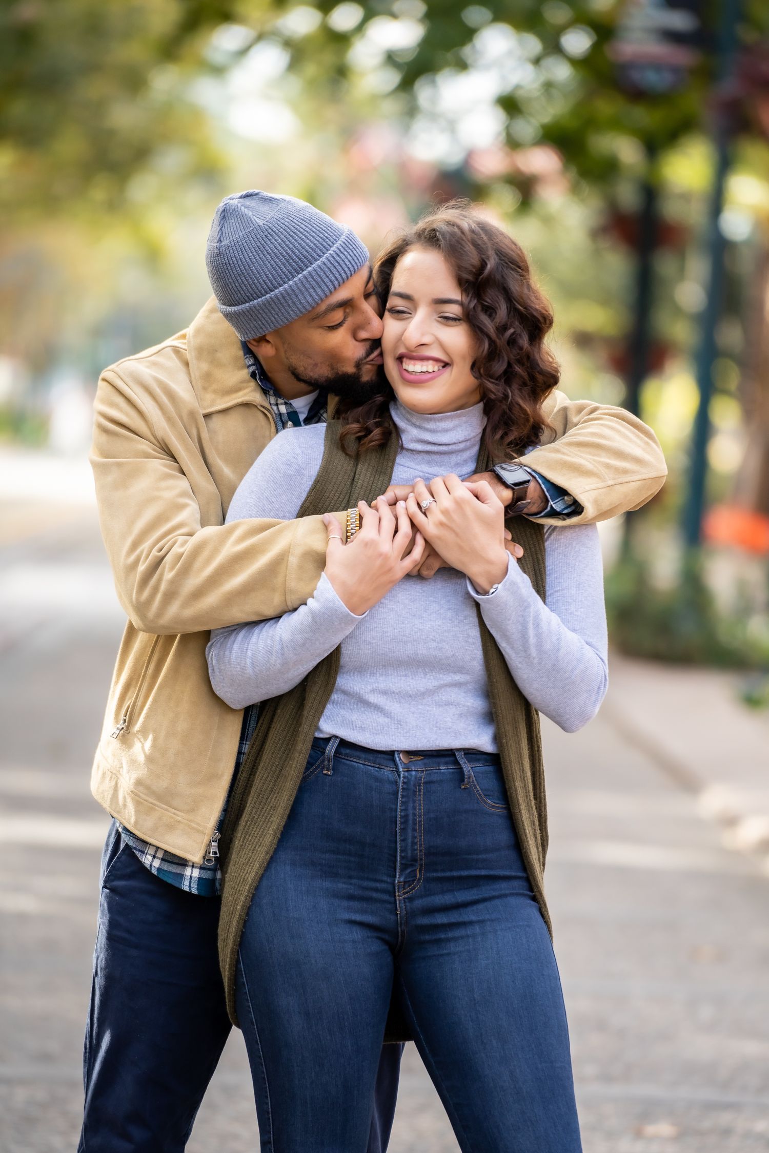 A couple shares an intimate embrace while wearing casual fall clothing outdoors.