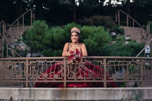 A red formal dress captured on stone steps with landscaped gardens in the background.