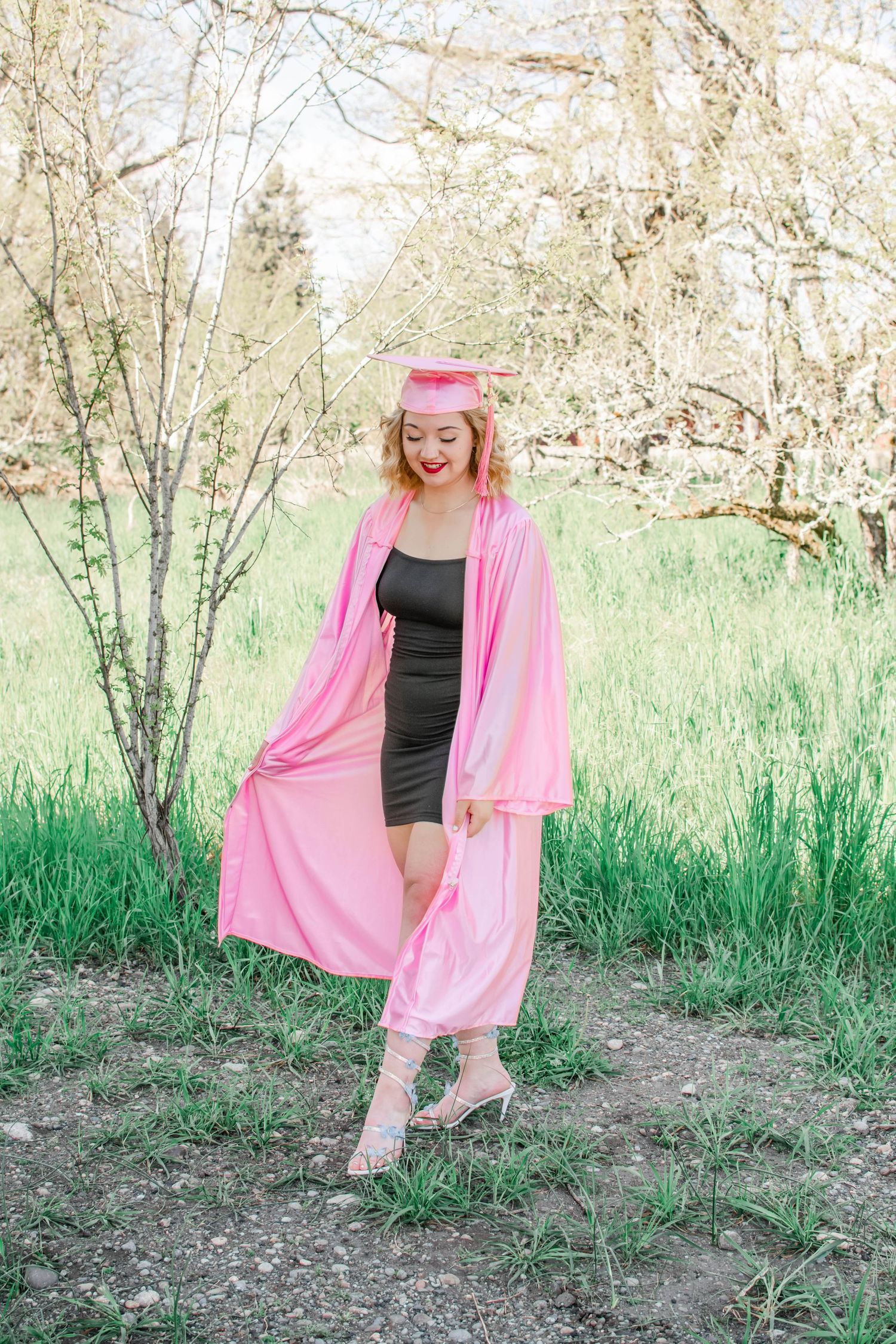 Outdoor fashion portrait in flowing pink robe and black swimsuit among spring foliage.