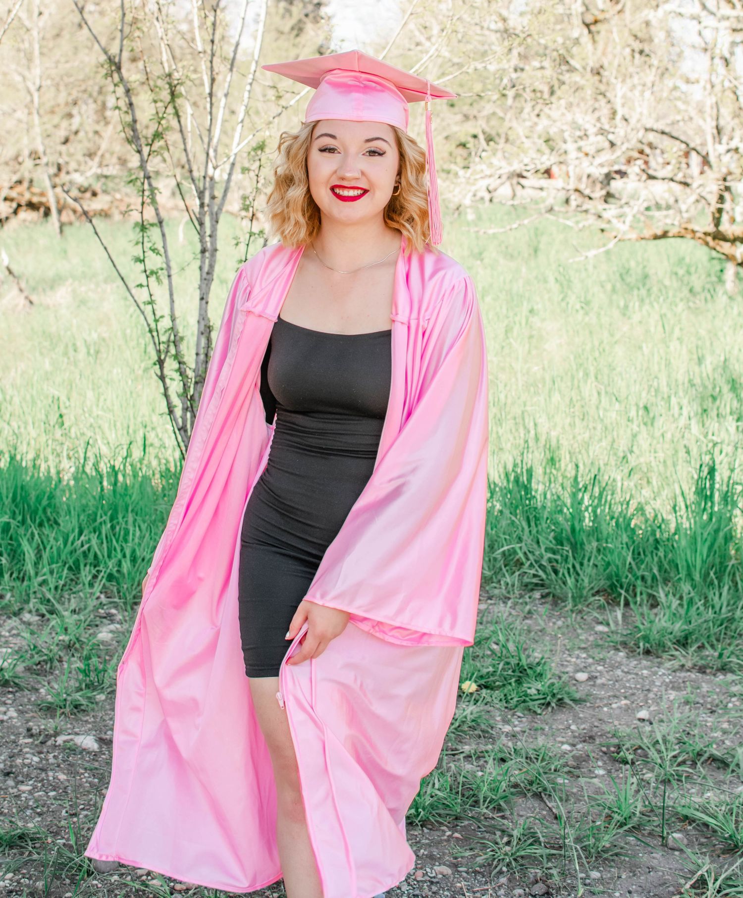Fashion model in pink kimono and black swimsuit poses in natural outdoor setting.