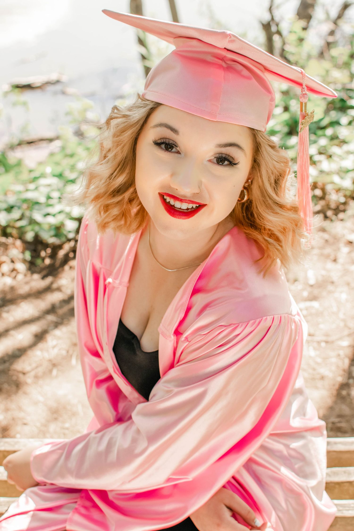 Playful graduation portraits in pink regalia with bright red lipstick.