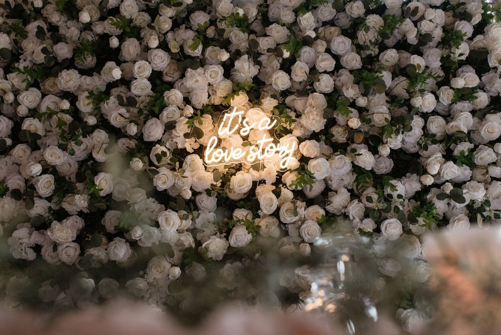Illuminated 'The End' neon sign surrounded by white floral arrangements creating a romantic wedding backdrop.