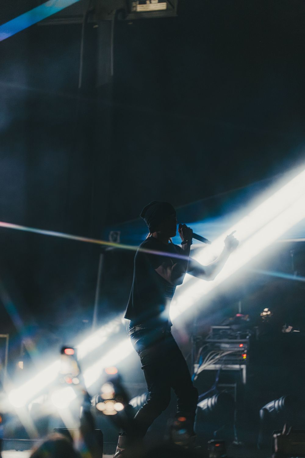 Dramatic silhouette of performer against bright stage lights and dark background during live show.