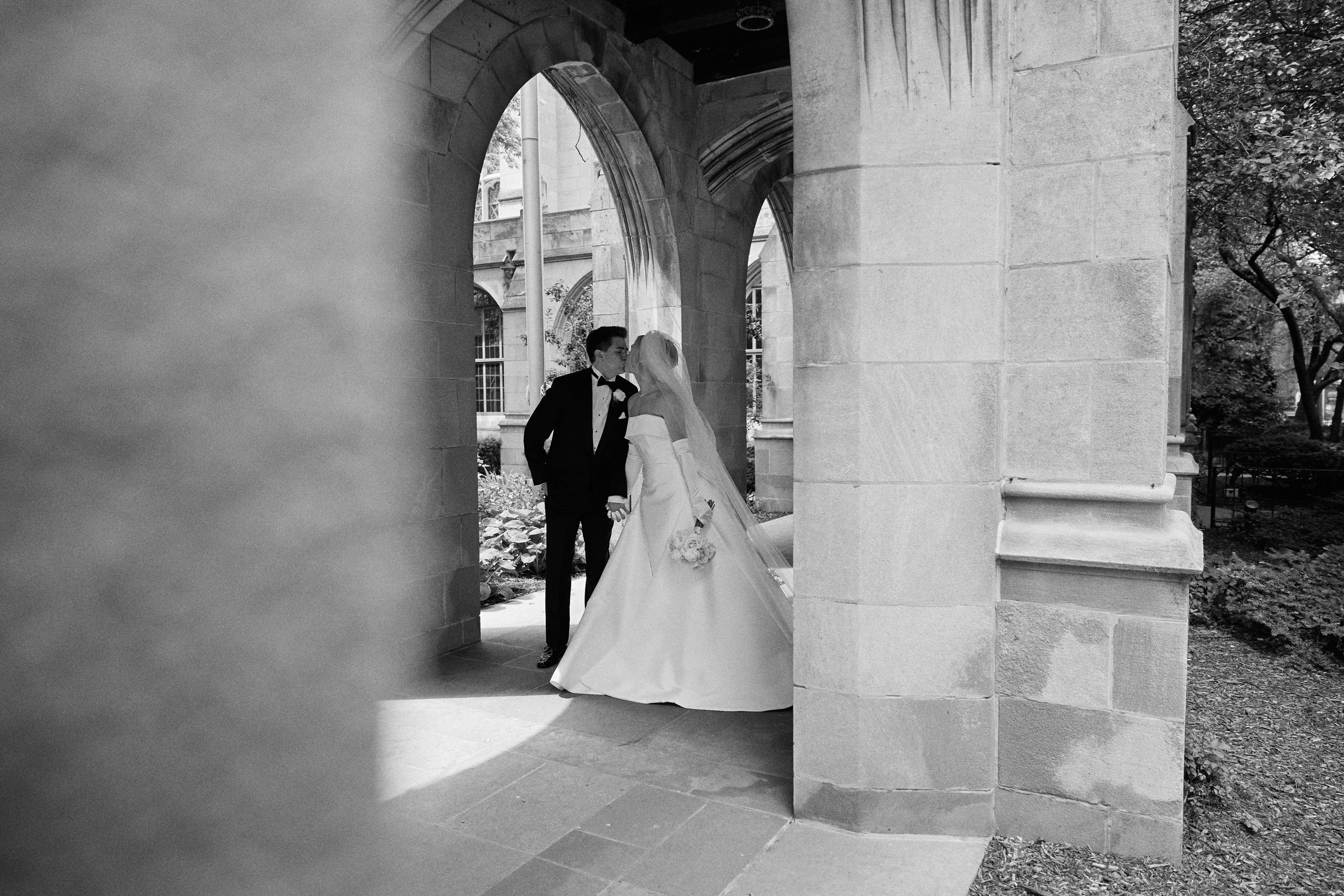 A series of black and white wedding photos showing couples in formal attire against a stone building backdrop.