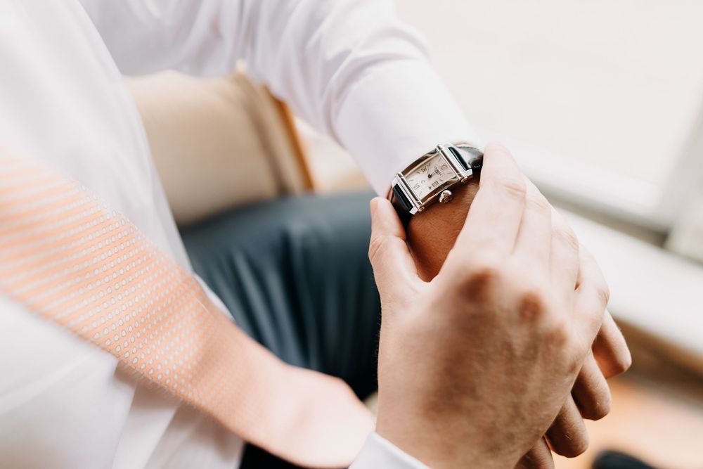 Close-up view of hands checking time on a modern smartwatch while wearing white sleeves.