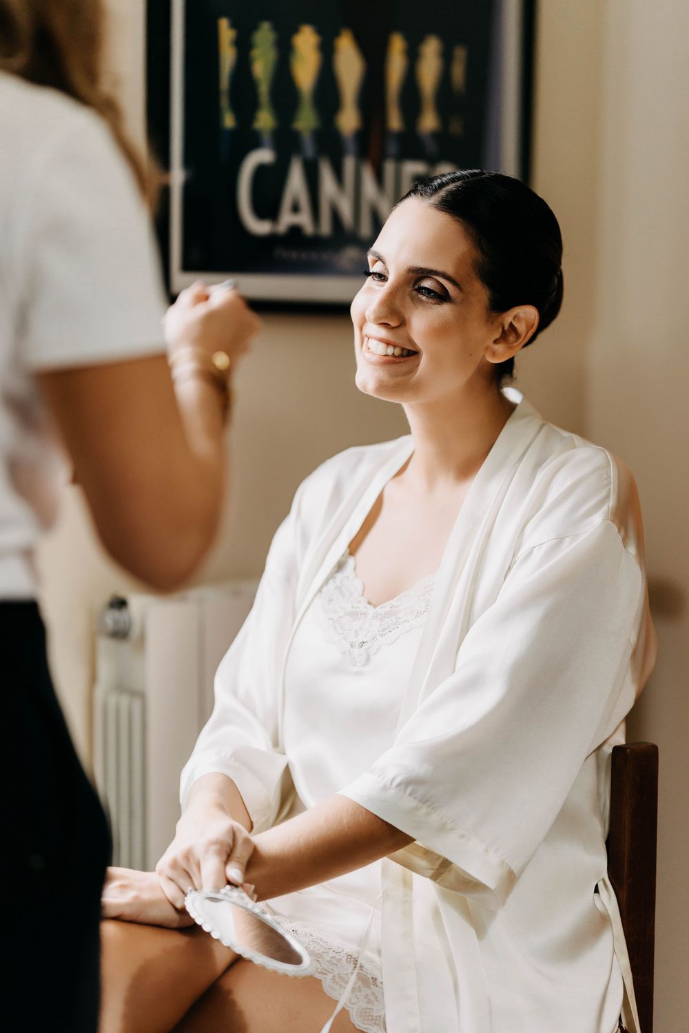 A person in a white outfit sits and smiles during what appears to be a candid moment in a casual setting.