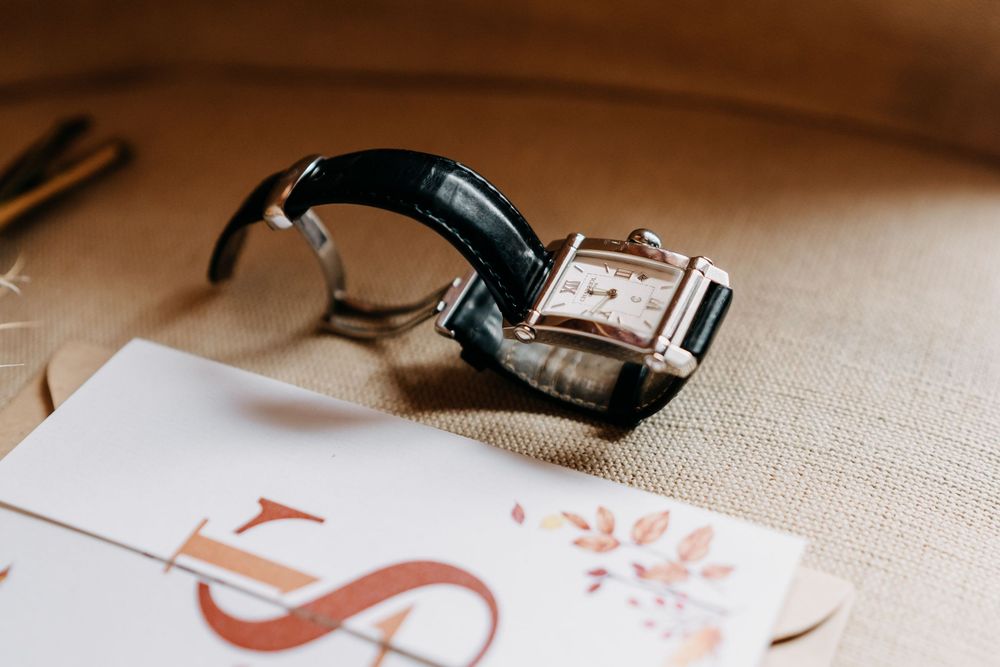 Close-up view of a vintage wristwatch with brown leather strap on a textured beige surface.