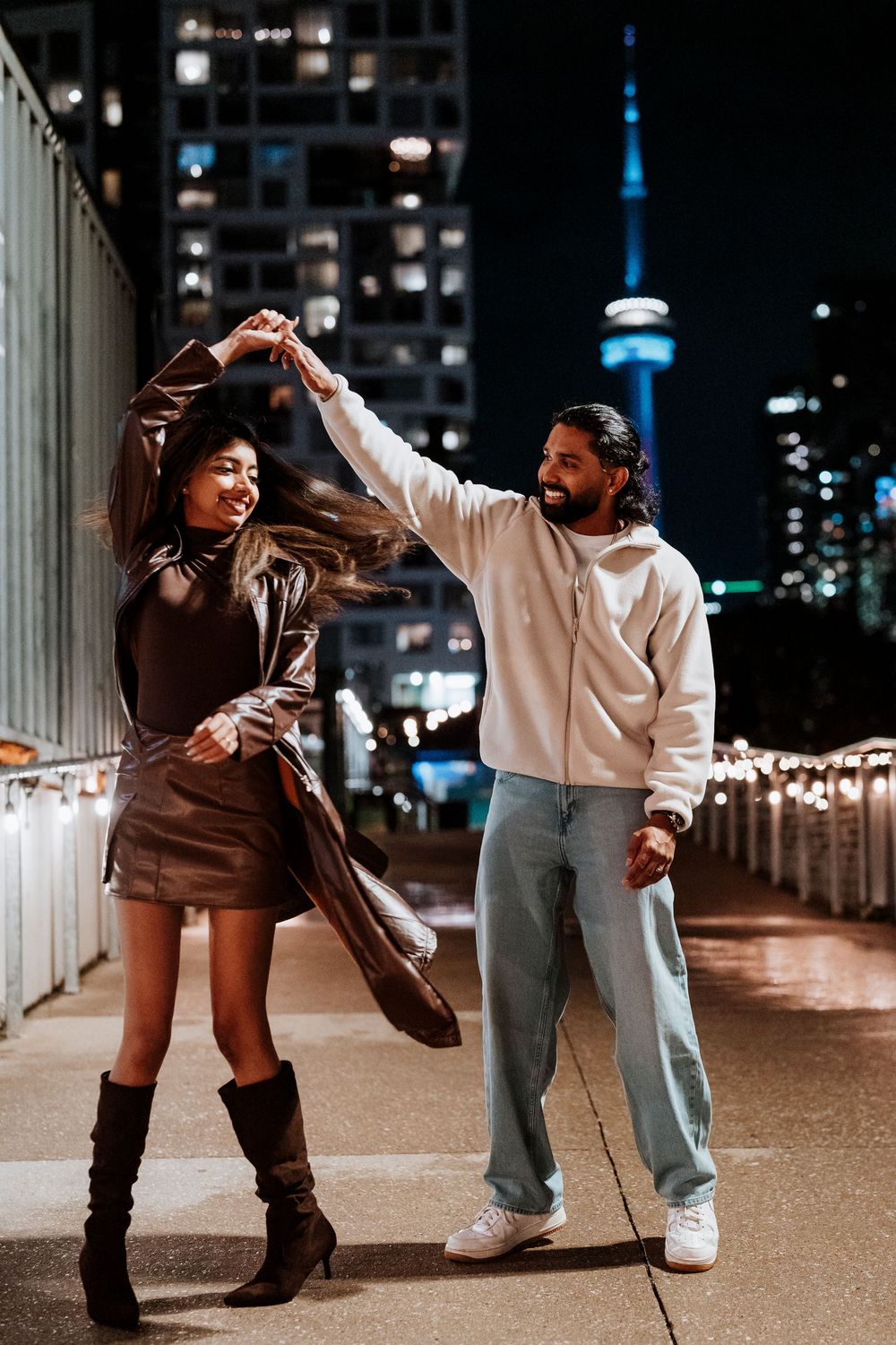 Two dancers performing dynamic urban dance moves at night with city lights in the background.