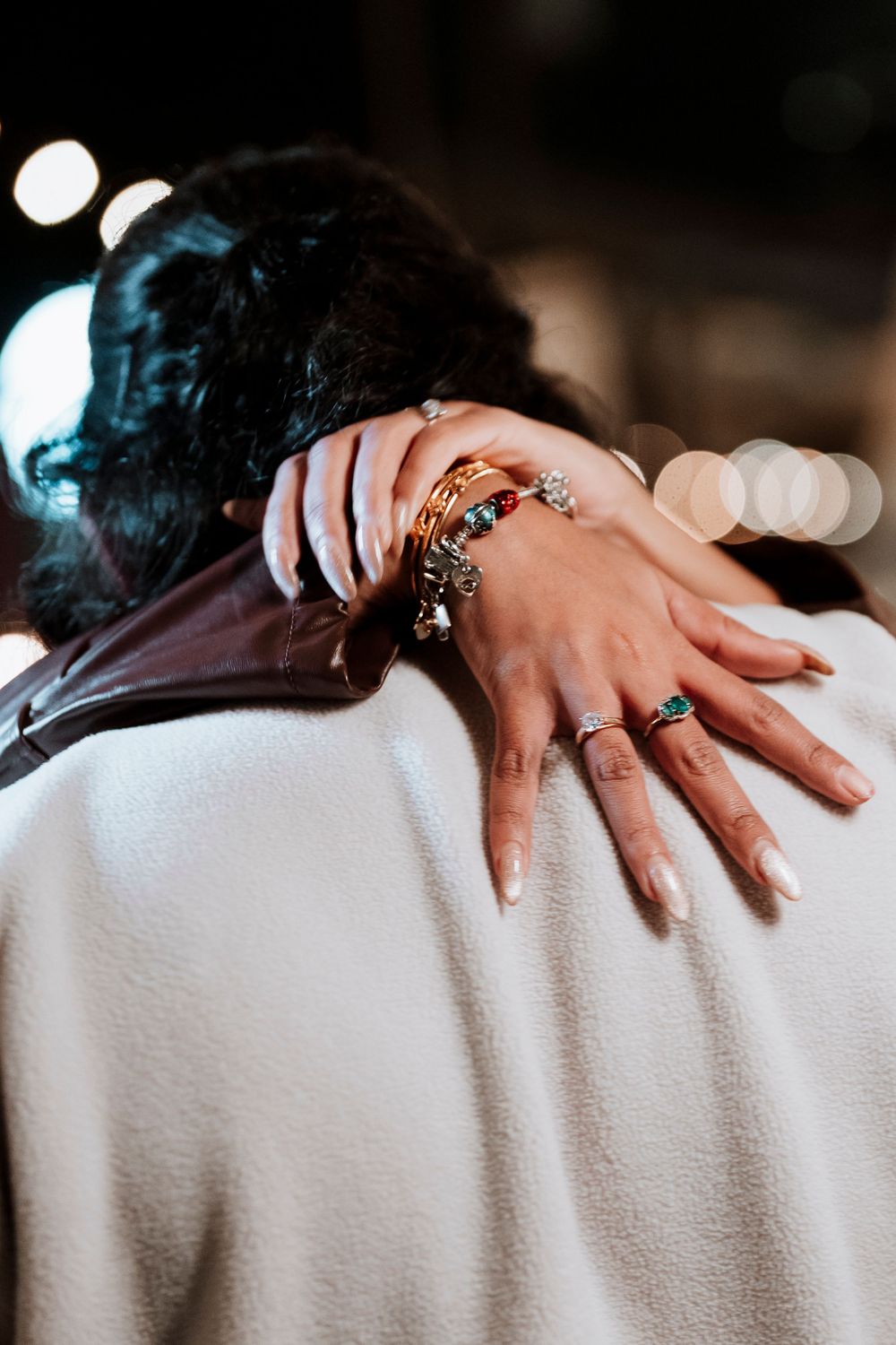 Close-up view of hands with rings resting on a white textured surface.