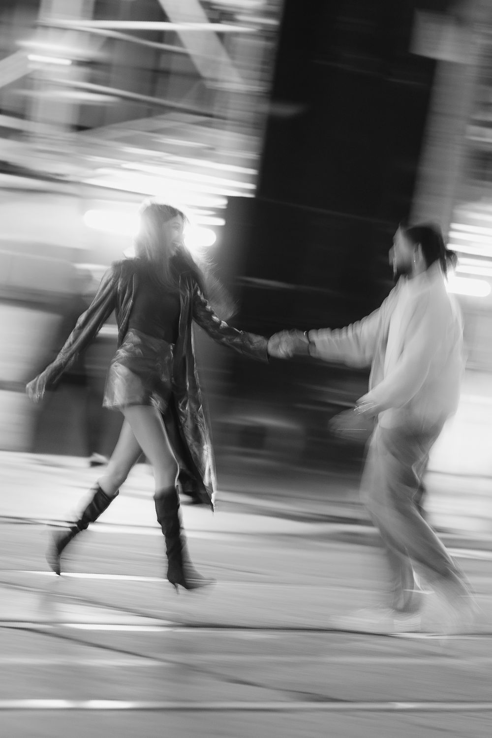 Black and white motion blur photograph of people ice skating at a rink with dynamic movement captured.