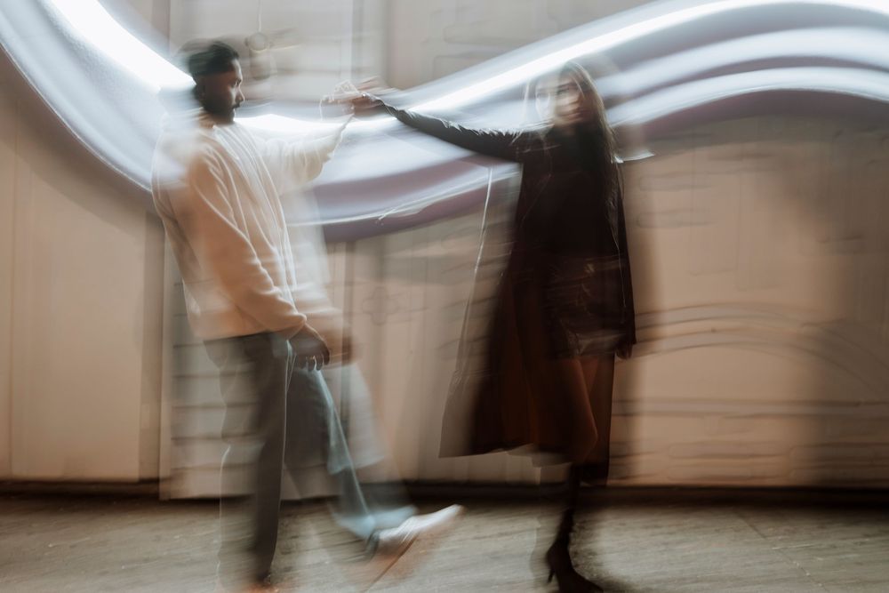 A series of motion-blurred photographs showing abstract figures moving through a white interior space.