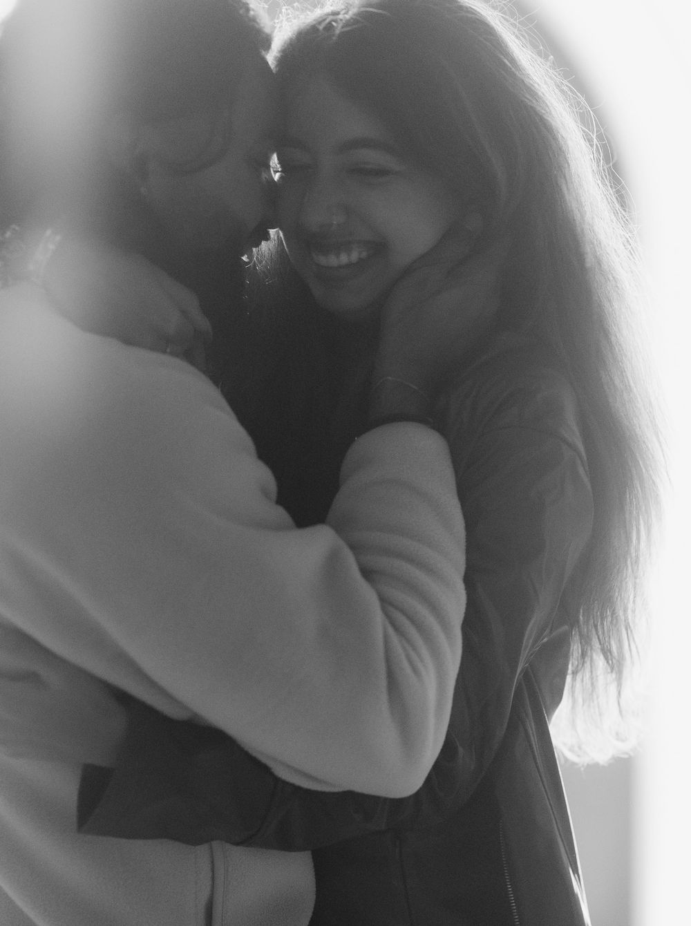 A black and white photo sequence shows two people sharing an intimate embrace and joyful moment together.