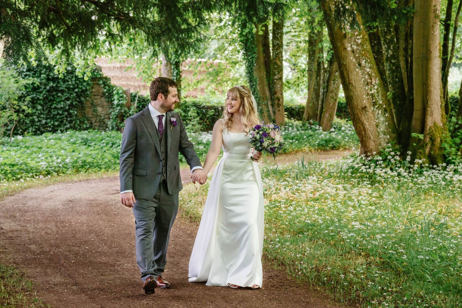Clearwell Castle wedding venue Gloucestershire castle summer wedding couple stroll through gardens