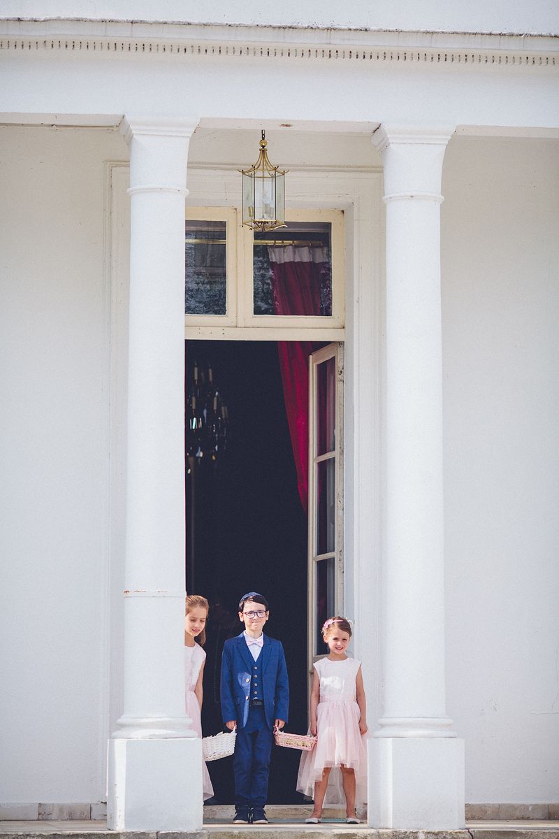 Flower Children standing at the garden entrance of Château Barthélemy during a wedding near Paris