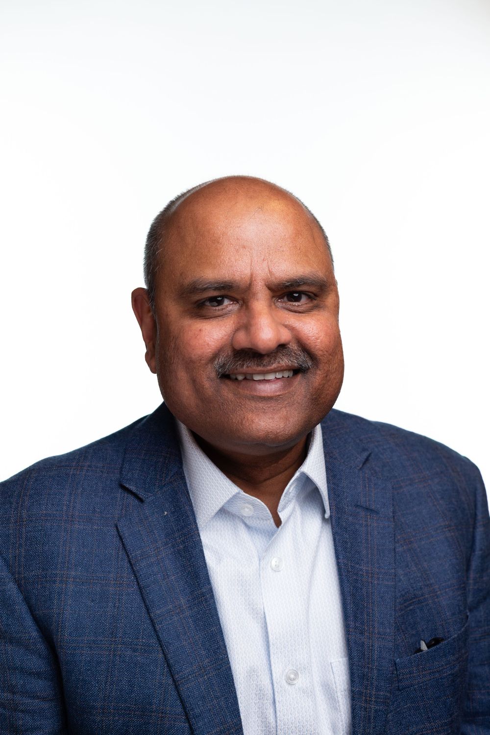 Professional headshot of a person in a navy blue blazer and light colored dress shirt against a white background.