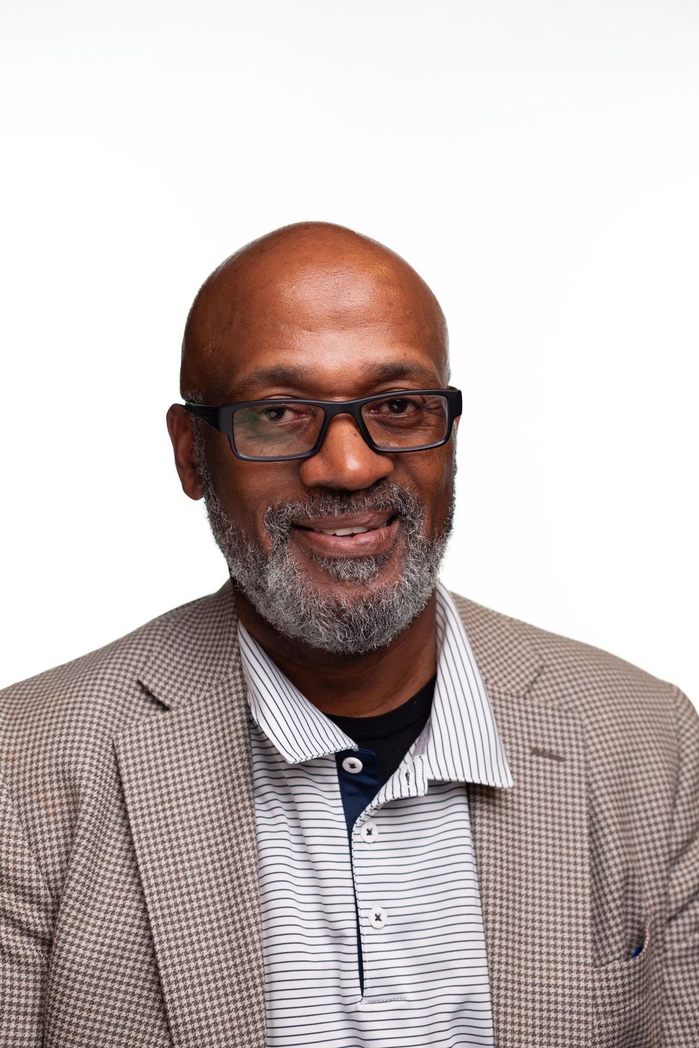 Professional headshots showing a person wearing glasses and a gray checkered blazer with a warm smile.