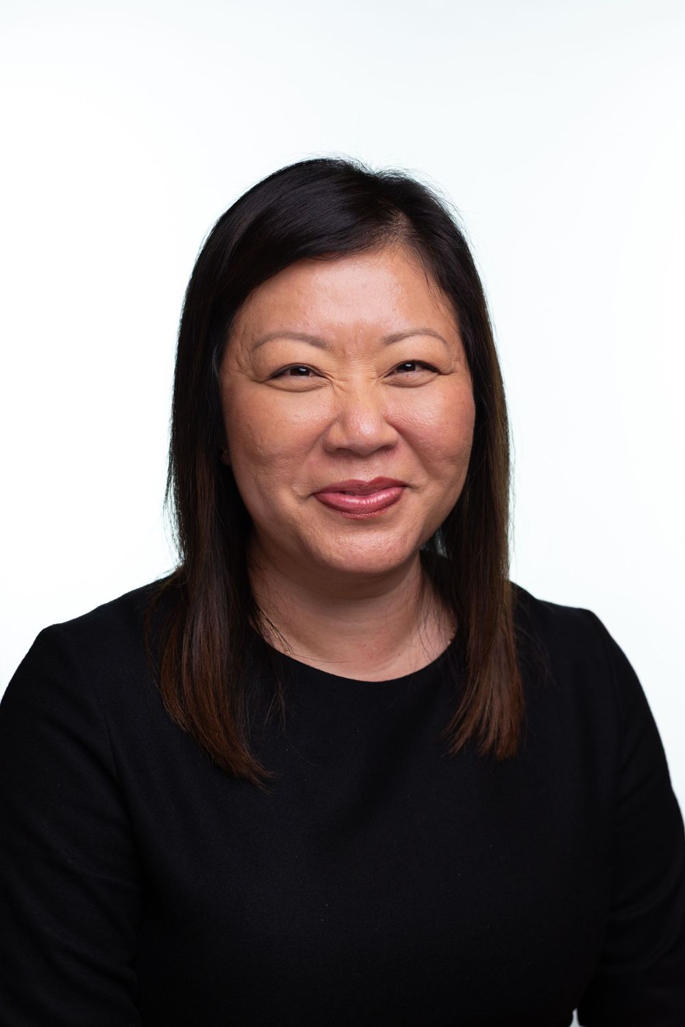 Series of headshots featuring someone in black attire displaying various cheerful expressions against white backdrop.