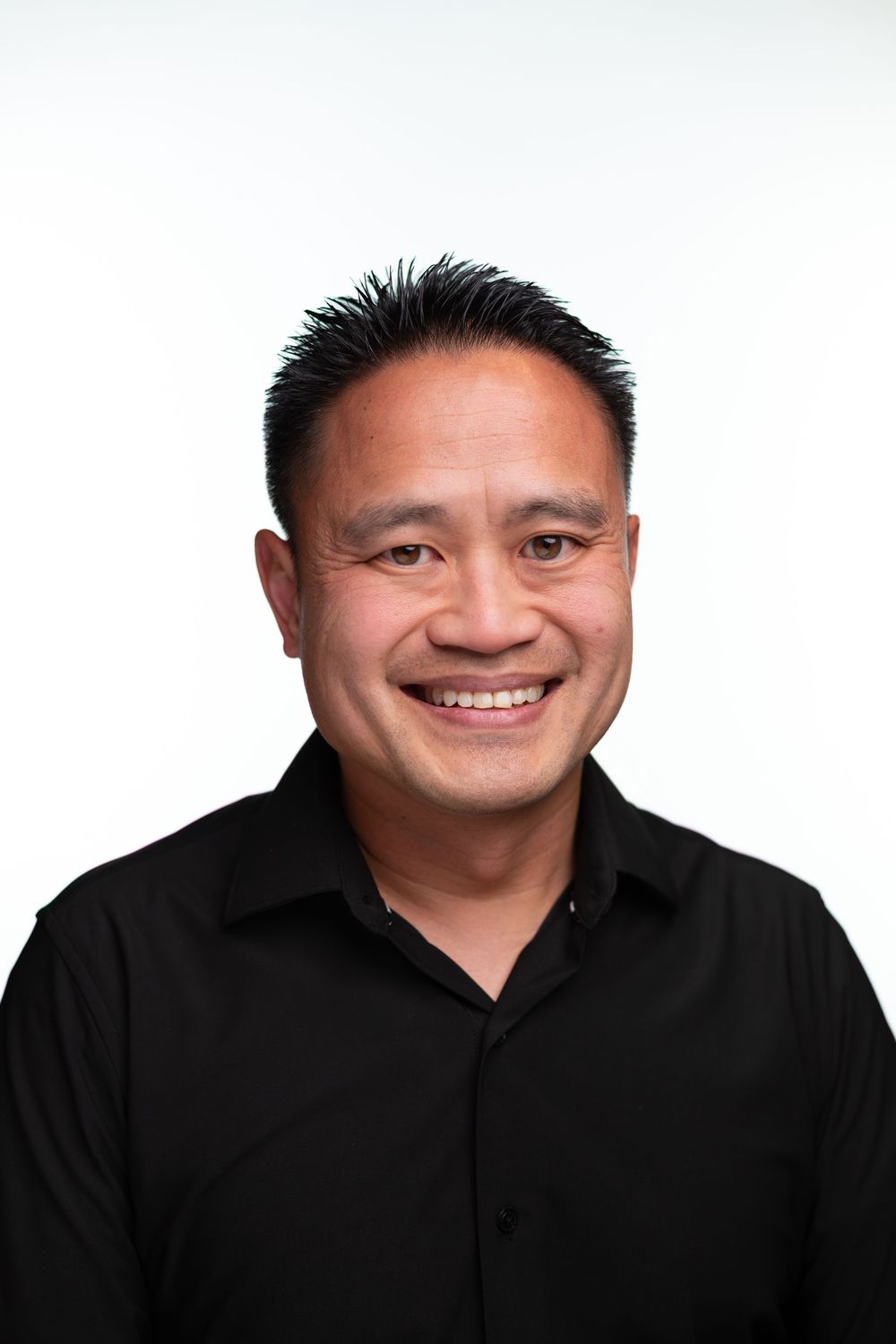 Four headshots showing progressively wider smiles while wearing a black polo shirt.