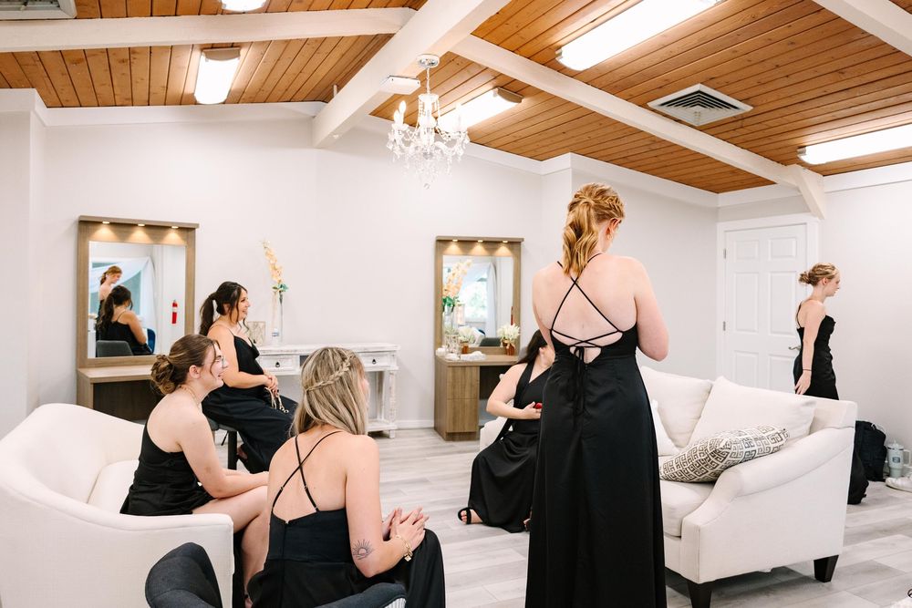 A group of people dance together in an elegant white studio space with wooden beam ceilings.