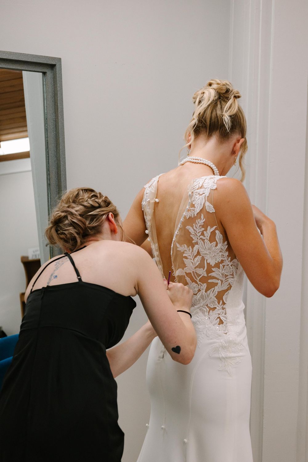 A sequence of photos showing someone in a black dress helping another person adjust a white lace wedding gown.