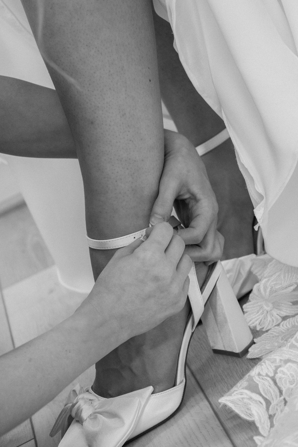 A series of black and white photos showing hands putting on white ballet shoes with ribbons.