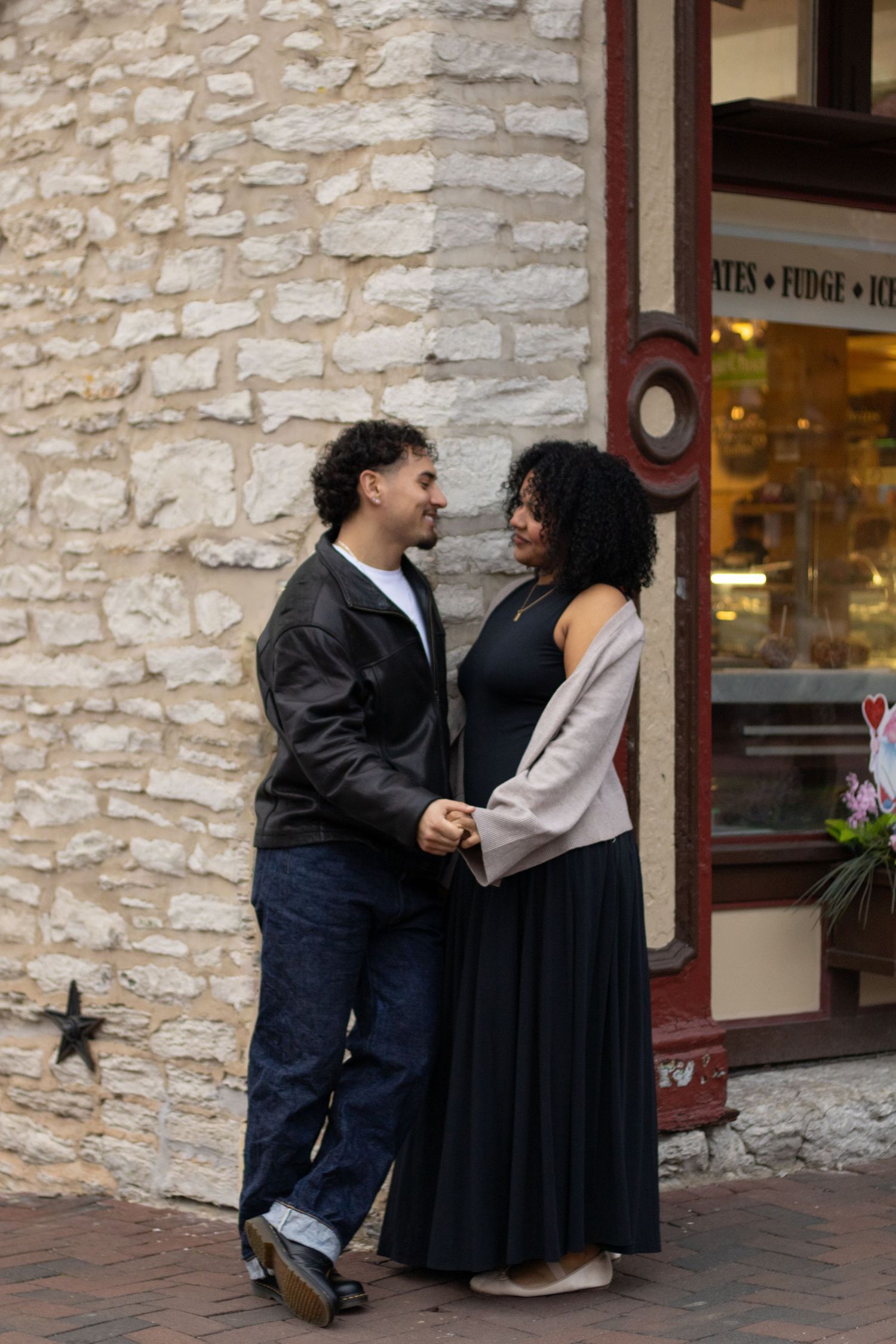 Two people share an intimate moment against a rustic stone wall exterior.