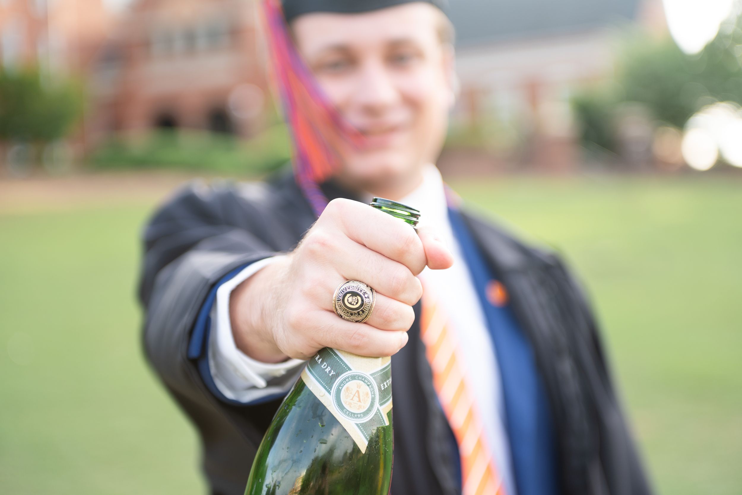 A row of champagne bottles being popped in celebration outdoors with spraying bubbles and formal attire.