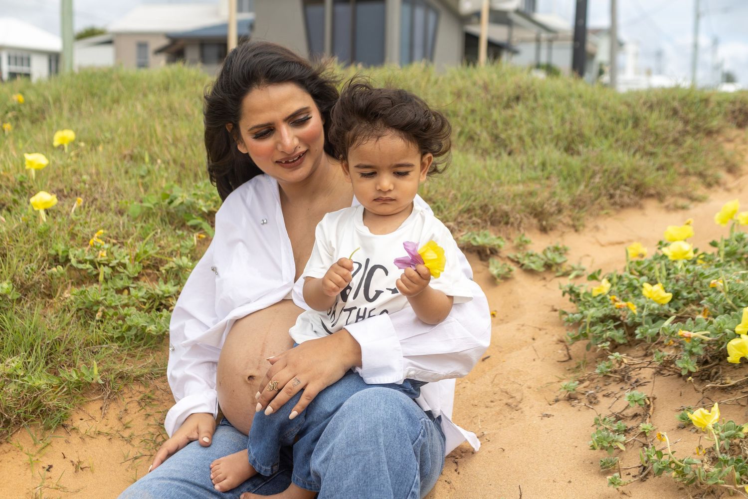A tender moment captured between a parent and child sitting together with yellow wildflowers.