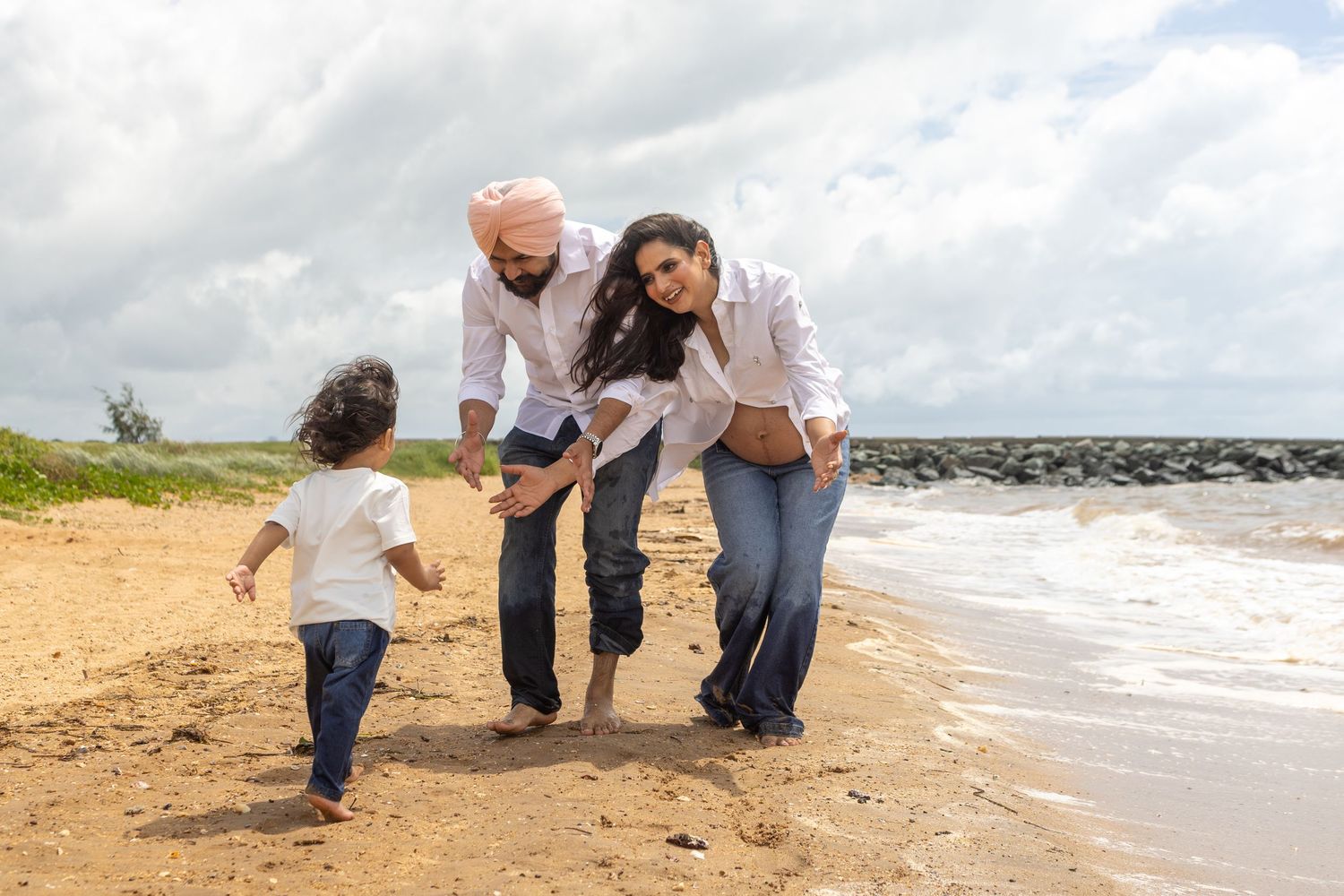 Family walking along a sandy Brisbane beach shoreline during sunset while holding hands and enjoying quality time together.