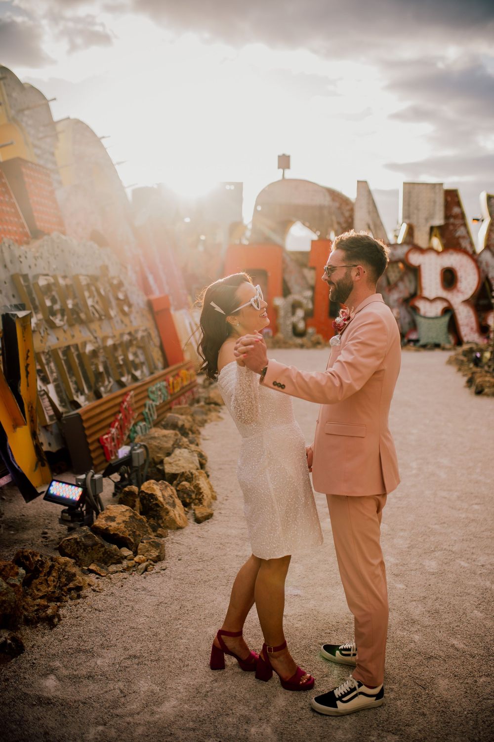 A couple shares a romantic moment at sunset at the iconic Neon Museum in Las Vegas, surrounded by vintage signs.